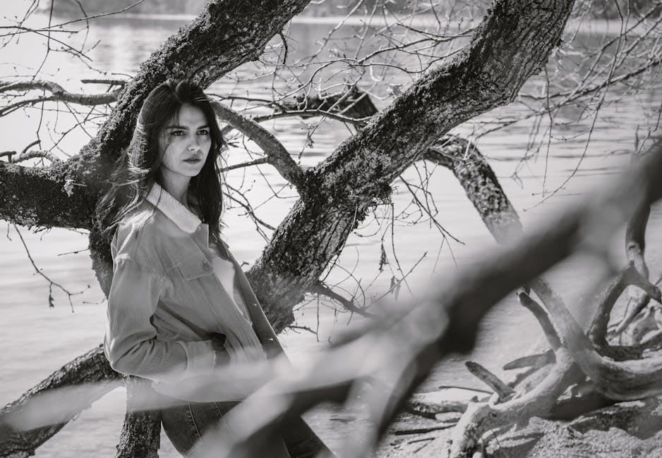 Black and white portrait of a woman outdoors by lake and tree in Morges.